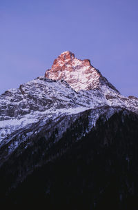 Low angle view of snowcapped mountain against clear blue sky