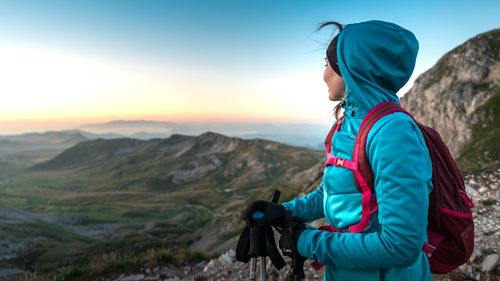 Side view of man standing on mountain against sky