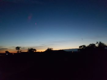 Silhouette trees against sky at sunset