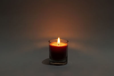 Close-up of illuminated tea light candle in darkroom