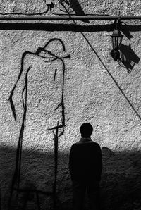 Rear view of silhouette man standing against wall