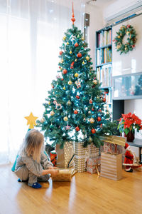 Full length of siblings playing with christmas tree at home