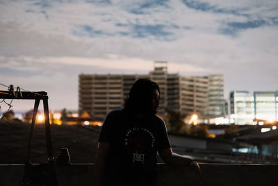 Rear view of woman looking at cityscape against sky