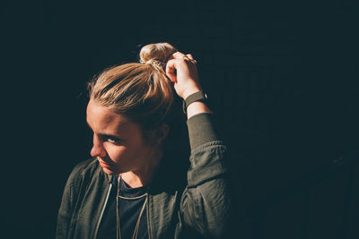 Close-up of young woman against black background