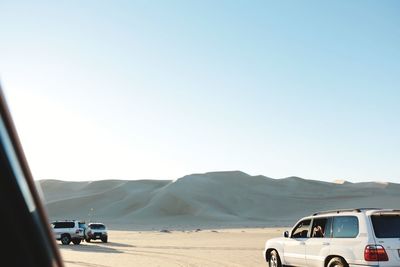 Off-road vehicles on desert against clear blue sky