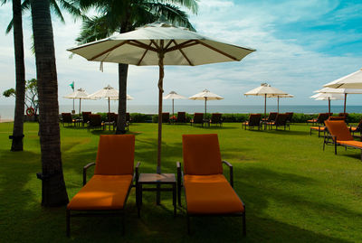 Chairs and tables on beach against sky