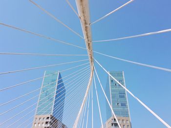 Low angle view of suspension bridge against clear blue sky