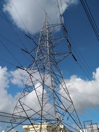 Low angle view of electricity pylon against blue sky