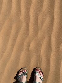 Low section of woman standing on sand