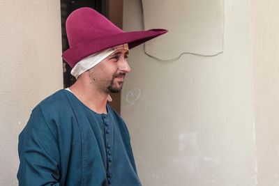 Man looking away while standing against wall