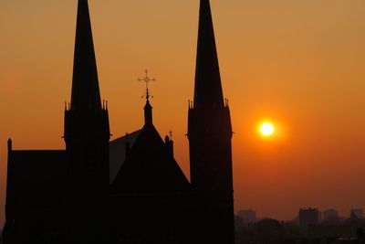 Silhouette of temple against building during sunset