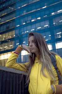 Young woman against yellow building