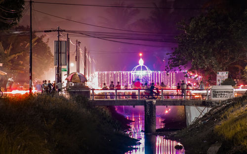 Illuminated bridge over river in city at night