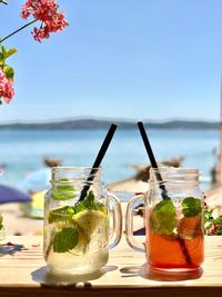 Close-up of drinks on table at beach against clear sky