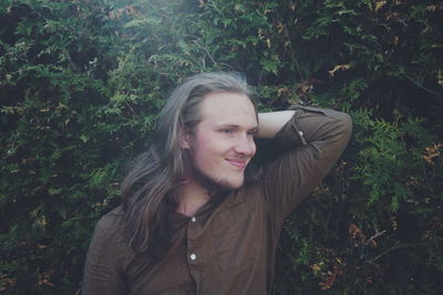 Young man with hand hair standing by plants