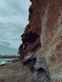 Rock formation on sea shore against sky