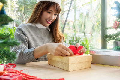 Young woman preparing christmas present at home