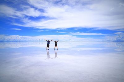 Full length of young woman standing in sea against sky