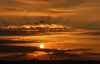 Low angle view of silhouette airplane against sky during sunset