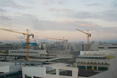 High angle view of cranes against buildings in city