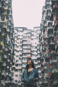 Smiling woman looking up against building in city