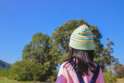 Rear view of girl standing against blue sky