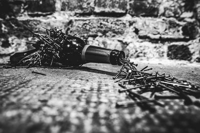 Close-up of damaged bottle with nails against wall