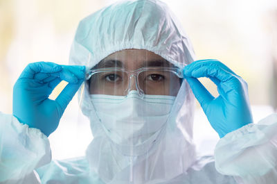 Closeup asian male doctor wearing face shield and ppe suit for coronavirus outbreak or covid-19