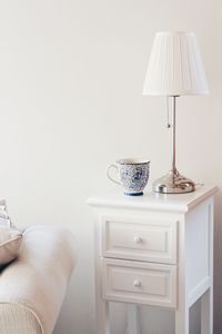 Cup and lamp shade on side table against wall at home