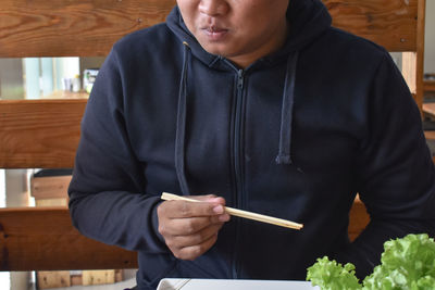 Midsection of man holding ice cream in restaurant