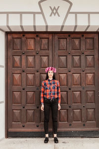 Portrait of woman standing against door