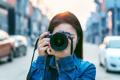 Close-up of woman photographing through camera in city