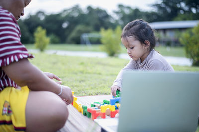 Young woman using laptop while sitting at park