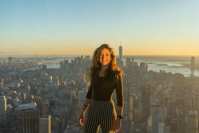 Portrait of woman standing against cityscape smiling