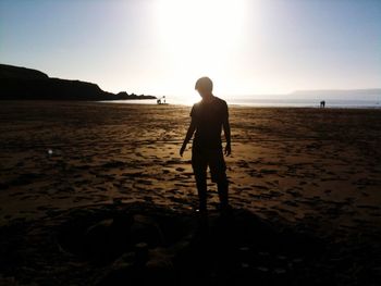Full length of silhouette man standing on beach against clear sky