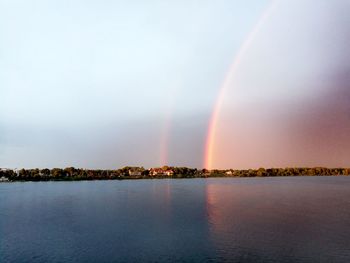 Scenic view of rainbow over river against sky