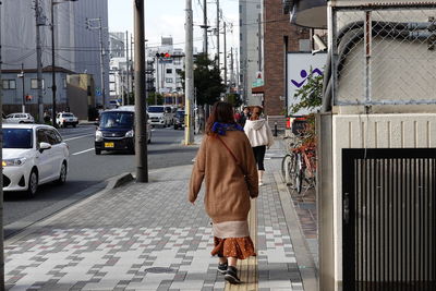 Rear view of woman walking on street in city