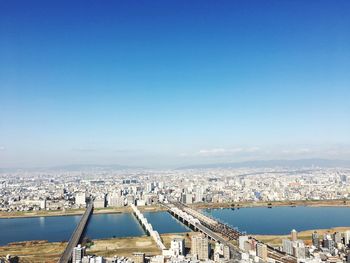 Aerial view of river and buildings against clear blue sky