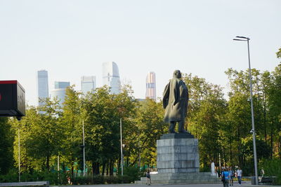 Statue against trees and city against clear sky