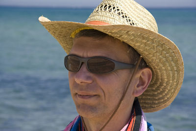 Close-up of man wearing sun hat against sea
