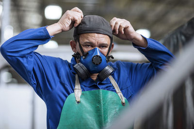 Worker putting on respirator in factory