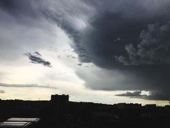 Silhouette of city against cloudy sky