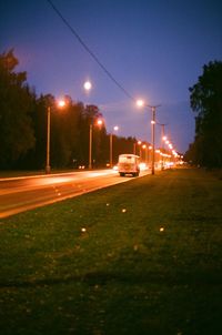 Illuminated road against sky at night