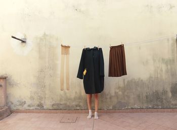 Low section of woman standing by clothes drying against wall