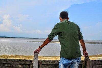 Rear view of man looking at sea against sky