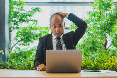 Young man using mobile phone while sitting on table