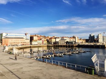 Harbor by buildings in city against sky