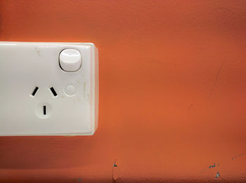 Close-up of doorbell on orange wall.