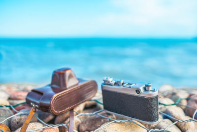 Close-up of camera on beach against sky