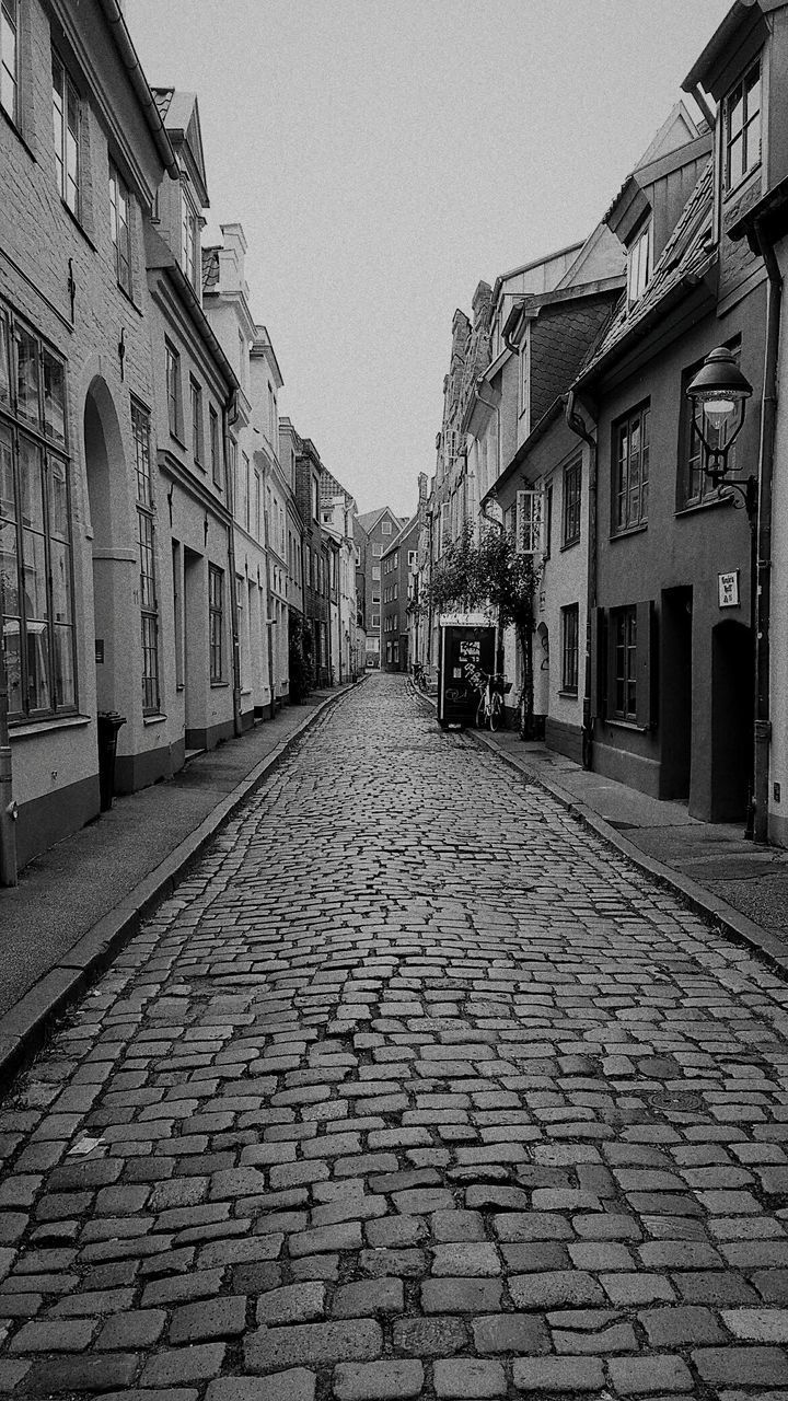 COBBLESTONE STREET AMIDST BUILDINGS AGAINST SKY